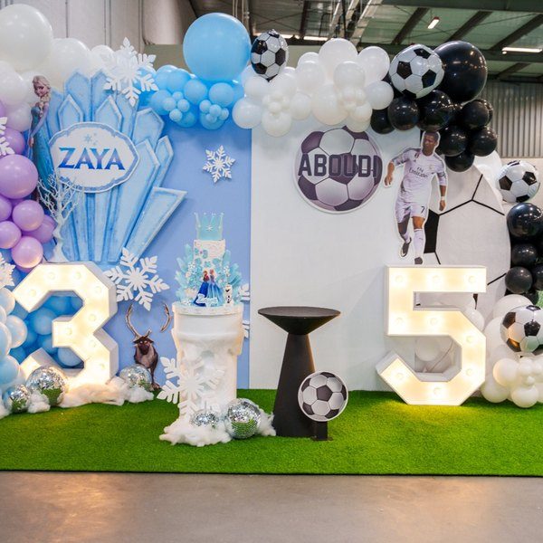Themed birthday backdrop with balloon garland and cake stand, Frozen and Football