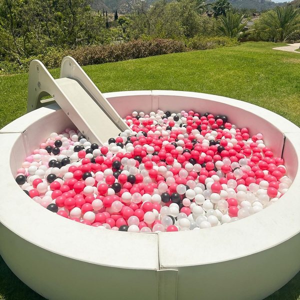 Round ball pit with slide filled with pink, white and black balls