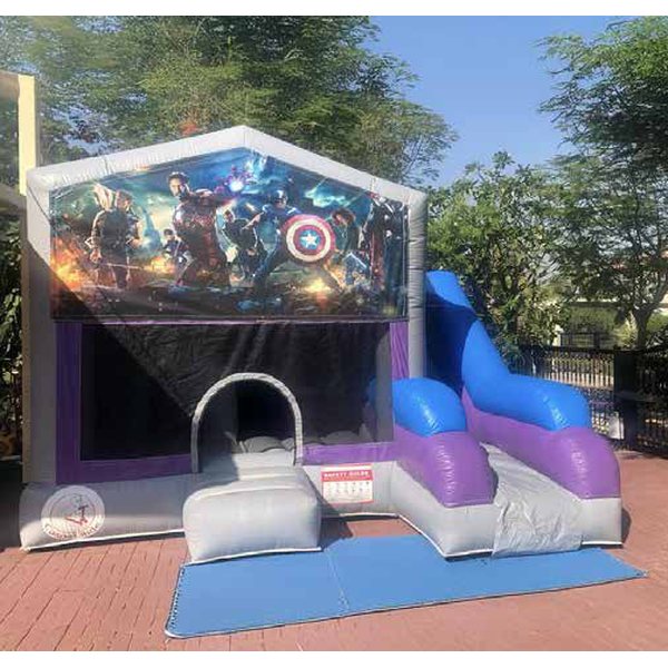 Bouncy castle with slide and superhero banners set up in a garden