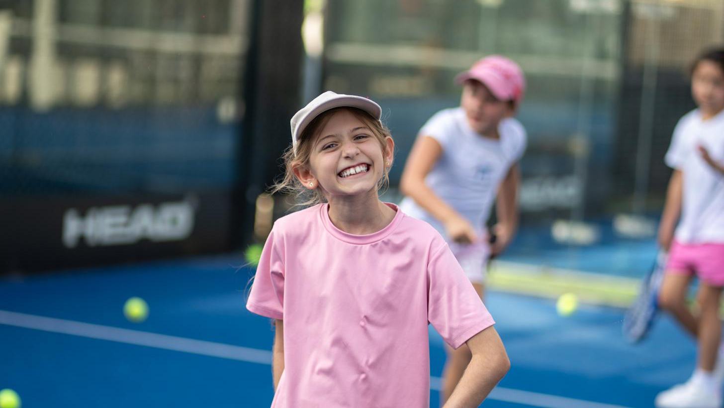 A smiling girl holding a padel racket on the court at the La Folie camp at Grip Sports, Dubai
