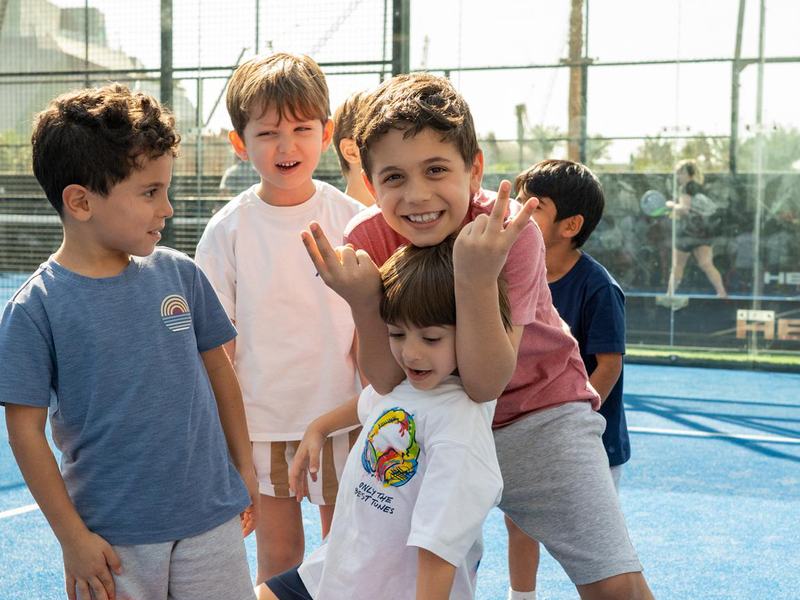 A group of boys laughing together on the court at La Folie's camp at Grip Sports, Dubai